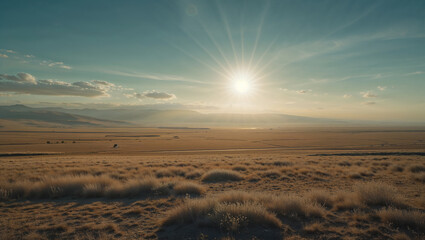 Fototapeta premium Sun shining over vast dry grasslands and mountains at sunset