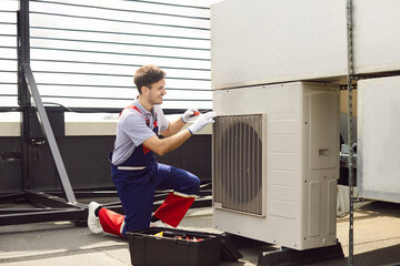 Obraz na płótnie Canvas Repairman performs an inspection, service, and fixing of an air conditioner HVAC system on a roof. The worker ensures the proper support and operation of the climate equipment during service.