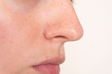 Fototapeta premium Macro shot of a woman’s nose and cheek skin with visible pores, texture, and natural imperfections. Ideal for skincare, dermatology, or cosmetic treatment projects.