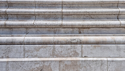 A detailed close-up reveals the textured surface of an old, weathered stone facade with horizontal...