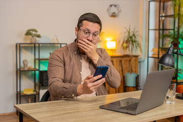 Oh my God, Wow. Caucasian young businessman using smartphone shocked by sudden victory game...