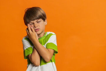 Dental problems. Young preteen child boy kid touching cheek, closing eyes with expression of...
