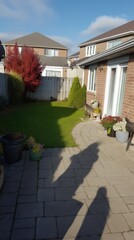 Mesh fence shadow casting across yard, background showing trimmed lawn, brick patio and potted plants.