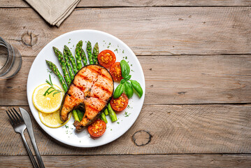 Grilled salmon steak with green asparagus, tomatoes and lemon slices