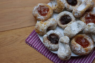 Traditional italian cookies with apricot and balckberries jam on a white plate on wooden table