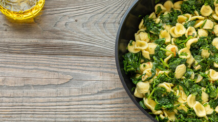 A pan with orecchiette pasta with broccoli rabe (rapini). South Italian dish. Olive oil in a...