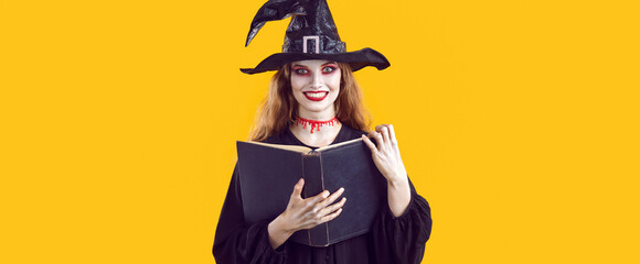 Portrait of woman in witch costume using spell book during Halloween celebration. Woman in witch's...