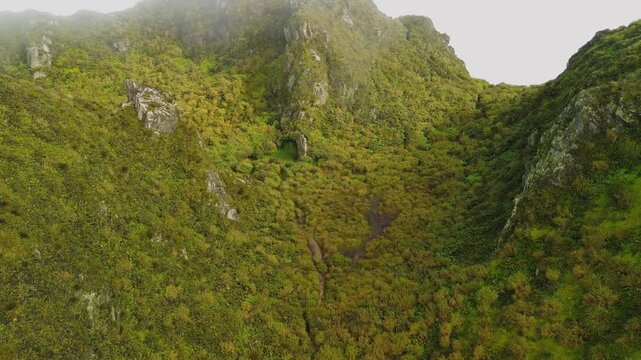Low morning clouds brush moss-covered ridges and a grassy basin near Mount Apo&rsquo;s summits, exposing rugged rock faces, alpine vegetation and a winding high-altitude trail above Mindanao.