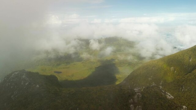 From Mount Apo&rsquo;s 2 952 m peak, soft dawn light reveals a patchwork of ridges, a tiny tarn and drifting cloud shadows across the high grassland valley of Mindanao.
