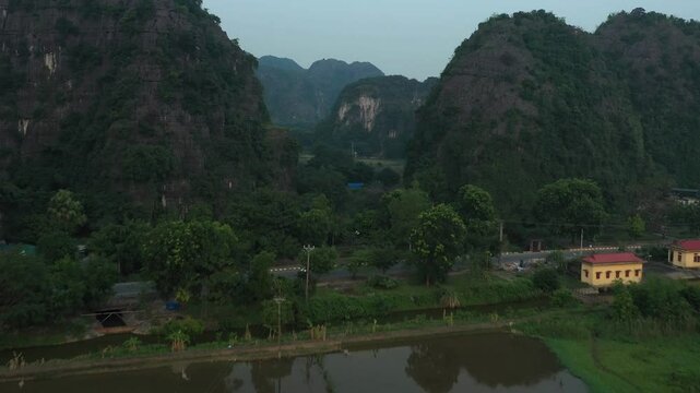Verdant landscape revealing rocky mountain peaks and winding river valley in Ninh Binh's pristine Vietnamese countryside during soft morning light