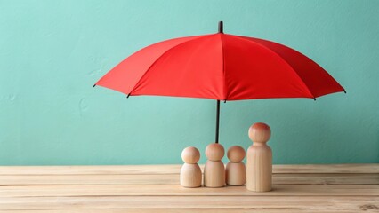 Red umbrella protecting wooden family figures on a wooden surface against teal background protection