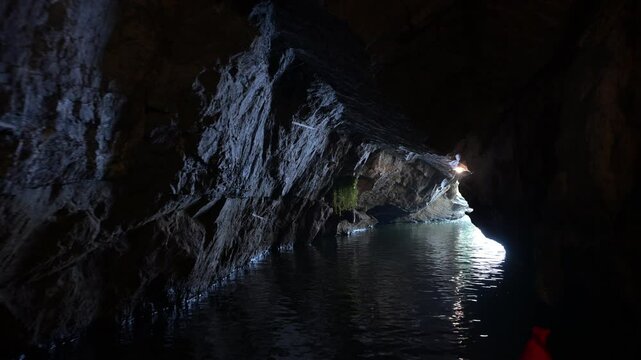 River flowing in the cave in Ninh Binh, Vietnam. Dark underground water, illuminating narrow cave entrance with gentle light reflection, revealing hidden geological wonder