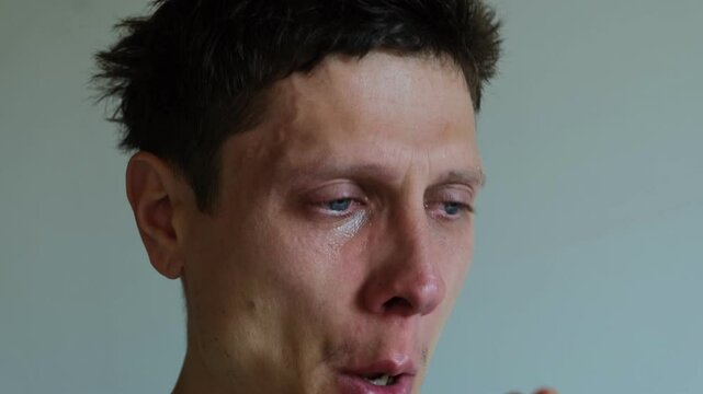 Close up of Crying man with tears in eye. Tear rolling down a man's cheek. A male wipes his tears