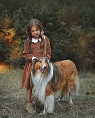 Beautiful little girl with a dog in the park in autumn