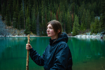 Woman sitting and holding a stick near lake