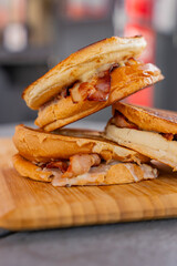 Zoom sur des burgers empilés et disposés sur une planche en bois. Burgers réalisés par un restaurateur spécialisés.