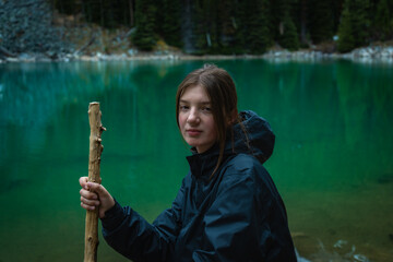 Woman sitting and holding a stick near lake