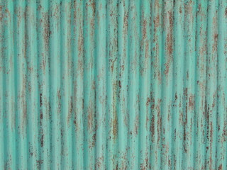 metal fence with traces of rust on peeling green painted surface, with relief ribbed texture, full frame, detailed texture of iron fence, vintage rough brown green background