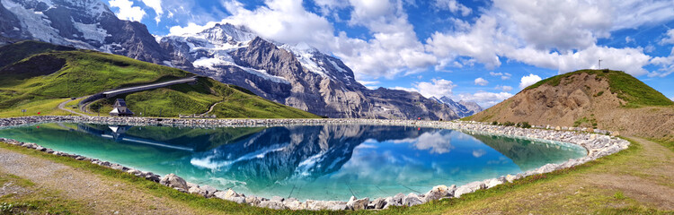 Switzerland nature . panoramic view of Fallboden lake with turquoise water and reflections of snowy peaks. Kleine Scheidegg mountain pass famous for hiking in Bernese Alps. Swiss travel