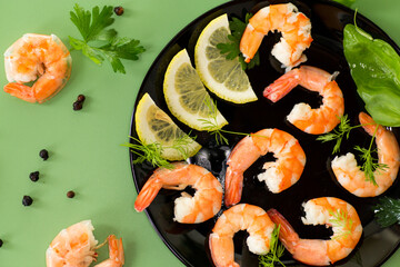 Juicy sea shrimps with lemon slices isolated on green background