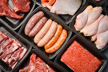 Black plastic packaging trays from supermarket with different types of fresh raw meat cuts, fresh beefbeef steaks, fish and variety meats in boxes from above