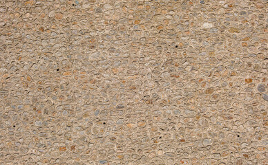 Textured huge stone wall. View of a textured stone wall featuring a variety of small stones arranged in a natural pattern. Use for themes related to architecture and natural materials.