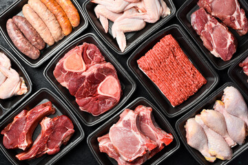 Different types of raw fresh meat and steaks in plastic boxes. Products from the market. Top view.
