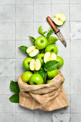 Ripe green apples in a linen bag. Close-up. On a stone background. Top view.