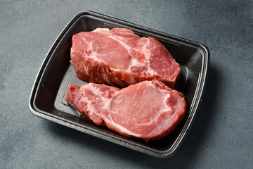 Raw meat. Fresh pork steak. Meat on a plastic black container from the market. Close-up.