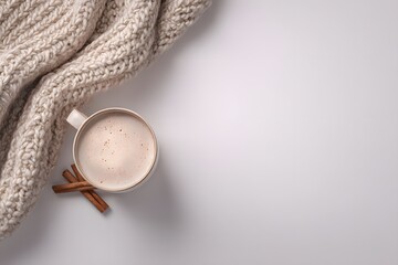 Fototapeta premium Cozy winter scene featuring a warm beverage, cinnamon sticks, and knitted blanket