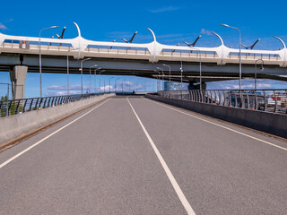 A stone bridge with concrete pillars. An empty road running along an overpass.