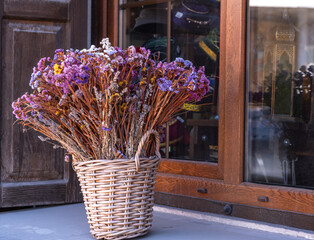 A bouquet of dried flowers in a basket on the windowsill.