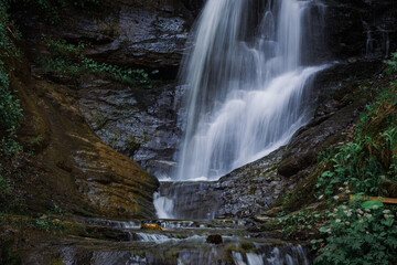 A waterfall cascades gracefully, creating a soothing sound as crystal-clear water tumbles over...