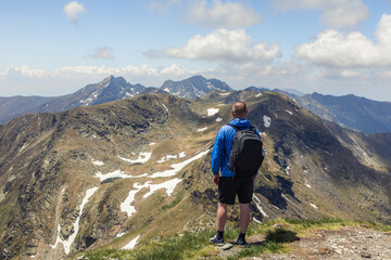 Fototapeta premium A man hiking through the mountains embraces adventure, surrounded by rugged trails, fresh air, and breathtaking views.