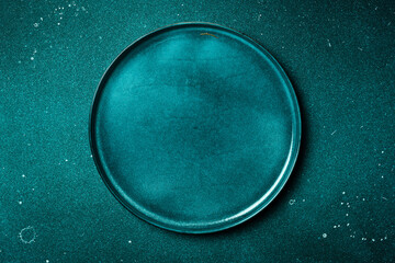 A round blue plate on a blue stone table. Free copy space. Top view.