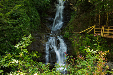 A waterfall cascades gracefully, creating a soothing sound as crystal-clear water tumbles over...