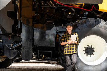 Female agricultural professional with tablet by combine harvester at equipment dealership