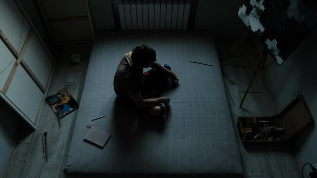 Disappointed painter alone in artistic space, poor and unhappy, lost in life.