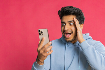 Happy excited Indian young man guy use smartphone typing browsing shouting say wow yes found out...