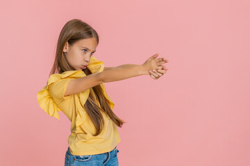 Young child girl enthusiastically mimics a finger gun gesture smiling with excitement and looking...