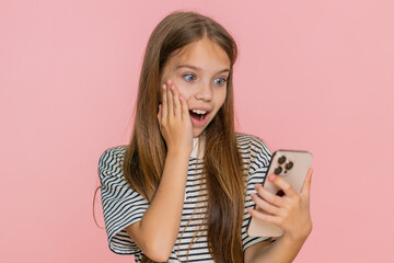 Young child girl happily plays an exciting mobile online game on smartphone, joyfully celebrating a...