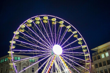 Lit up Ferris wheel with bright light in the middle on a dark December evening at Christmas market...