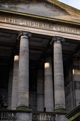 Front columns of The Supreme Courts in Edinburgh at sunrise. Golden letters on the historic building in sun light. Details of historic building vertical view. Edinburgh, UK, 05.05.2025