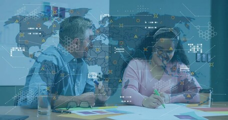 Man pointing at swatches, woman taking notes, digital map overlaying icons during business meeting - Powered by Adobe