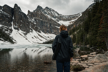 Hiker stands by snow-covered lake