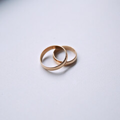 Two gold wedding rings are placed on a white background