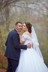A bride and groom are kissing each other's necks