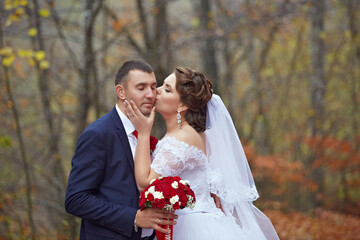 A man and woman are kissing in the woods