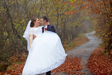A bride and groom are posing for a picture in a forest