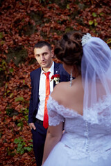 A man and a woman are standing in front of a wall covered in leaves